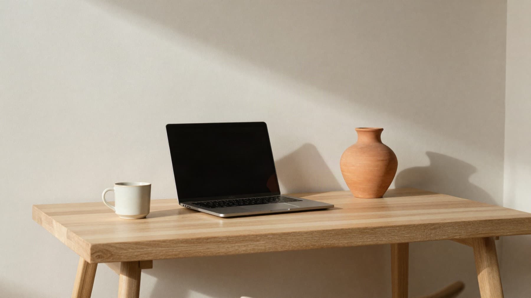 A minimal desk with a laptop in warm morning light